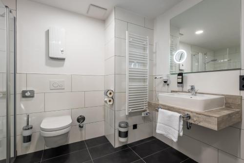 a white bathroom with a sink and a toilet at Trip Inn Hotel & Suites Essen in Essen