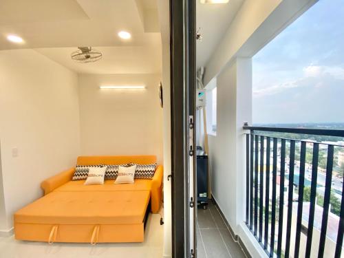 Cette chambre dispose d'un balcon et d'un canapé orange. dans l'établissement OSIMI building PHU MY - C1104, à Phú Mỹ