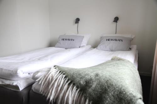 two beds with white sheets and pillows with a blanket at STF Hemavans Fjällcenter in Hemavan