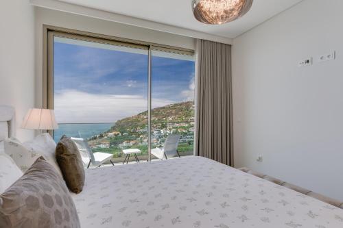 una camera con un letto e una grande finestra di Luxury Villa Bianca by HR Madeira ad Arco da Calheta