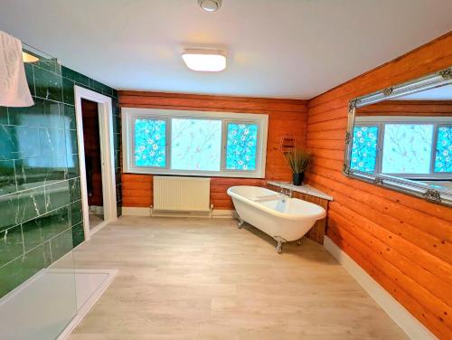 a bathroom with a tub and a sink and windows at Kaoglen Doe-Feature Bathroom-Cairngorms-Pets Allowed in Balnald
