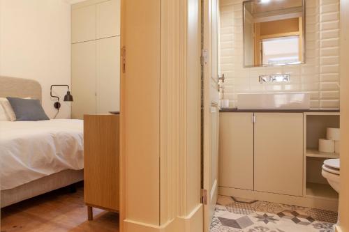 a bedroom with a bed and a bathroom with a sink at Charming 2BDR Apartment in Lapa by LovelyStay in Lisbon