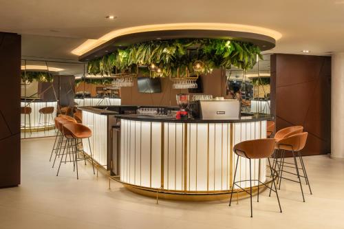 a bar in a restaurant with chairs and plants at Fagus Hotel Conference & Spa in Sopron