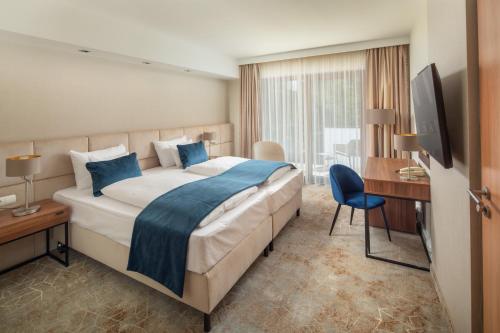 ショプロンにあるFagus Hotel Conference & Spa Superiorの大きなベッドとデスクが備わるホテルルームです。