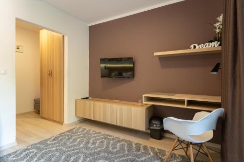 ein Wohnzimmer mit einem TV und einem weißen Stuhl in der Unterkunft Penzión ** Kolkáreň in Vyhne