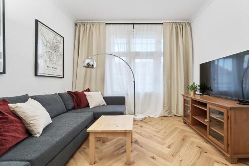 a living room with a gray couch and a flat screen tv at Family Apartment - 74m2 - Wapienna by Renters in Wrocław