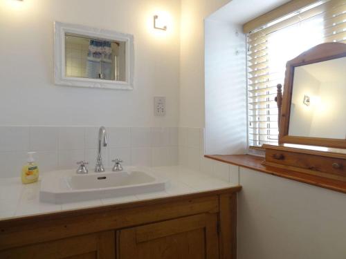 a bathroom with a sink and a mirror and a window at Fiddlesticks Cottage in Beaminster