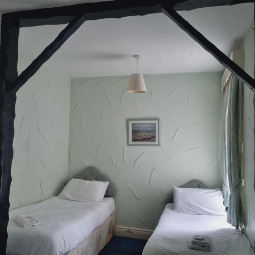 Dos camas en una habitación con paredes blancas. en The New Osterley Hotel, en Blackpool