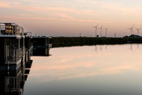 uma vista para um rio com turbinas eólicas ao fundo em Hausboot Wangermeer Nordsonne12 mit Sauna em Wangerland