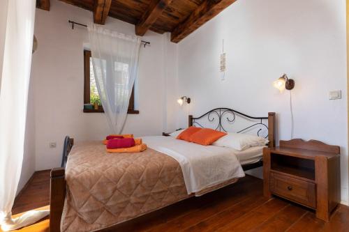 een slaapkamer met een bed met oranje kussens en een raam bij Rustic Villa Lara with pool in Čabrunići