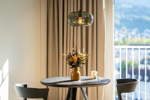 een tafel met een vaas met bloemen en een raam bij Black F Tower - Serviced Apartments in Freiburg im Breisgau