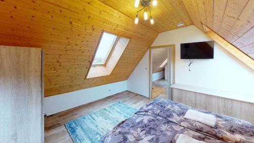 an attic bedroom with a bed and a tv at Apartmány U Mirase in Sedlec