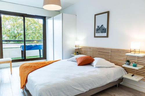 um quarto com uma cama grande e uma janela grande em Le Sperata - Bel appartement en centre ville avec 2 chambres, terrasse et parking em Pau