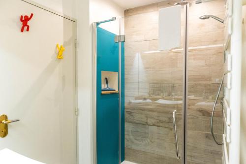 La salle de bains est pourvue d'une douche avec une porte en verre bleu. dans l'établissement Le Sperata - Bel appartement en centre ville avec 2 chambres, terrasse et parking, à Pau
