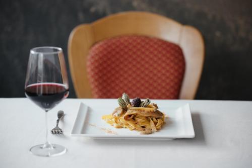 a plate of pasta and a glass of wine on a table at Hotel La Montanara Predazzo in Predazzo