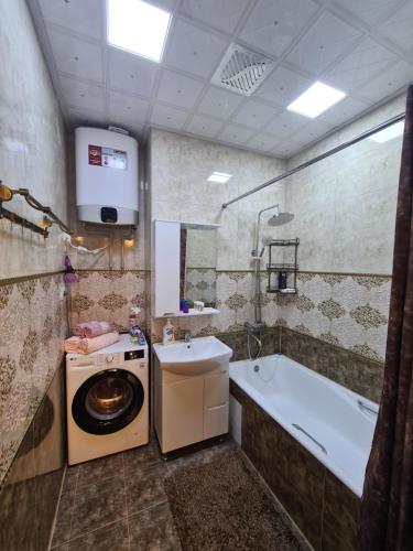 a bathroom with a tub sink and a washing machine at Excellent 2-room apartment bright and cozy in Dushanbe