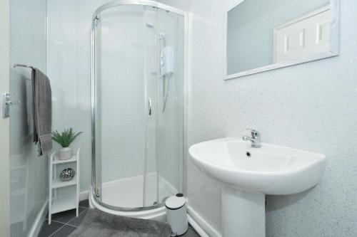 a white bathroom with a sink and a shower at Beautiful 3-Bed House by MiniStays Stoke-on-Trent in Stoke on Trent