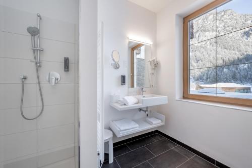 ein weißes Bad mit einem Waschbecken und einer Dusche in der Unterkunft Hotel Fischer am See in Heiterwang