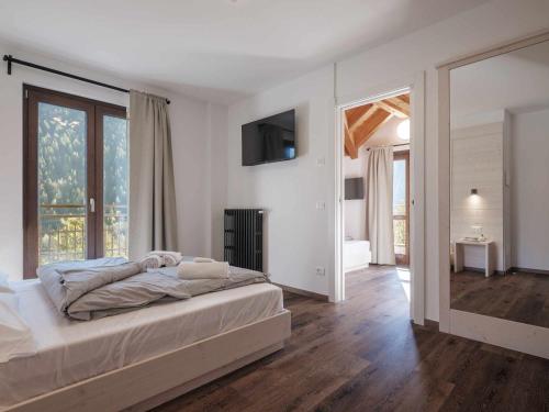 a white bedroom with a bed and a large window at Hotel Garnì Alta Valle in Ponte di Legno