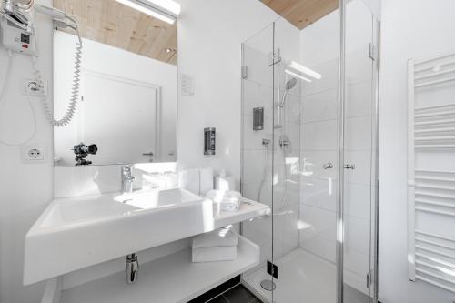 a white bathroom with a sink and a shower at Hotel Fischer am See in Heiterwang