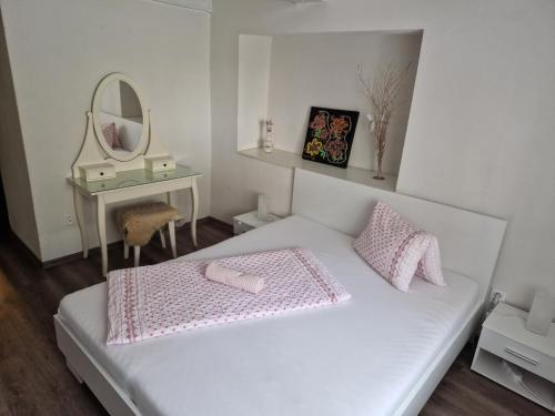 1 dormitorio con cama blanca, espejo y mesa en Apartmany St. Maria, en Staré Hory