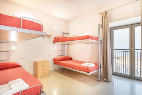 a bedroom with bunk beds and a balcony at Albergue Inturjoven Chipiona in Chipiona