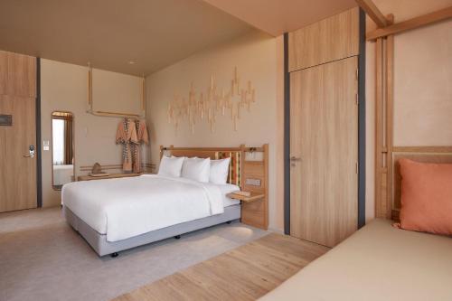 a bedroom with a large white bed and a closet at Centara Korat in Nakhon Ratchasima