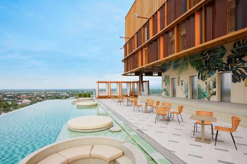 a building with a pool with chairs and tables at Centara Korat in Nakhon Ratchasima