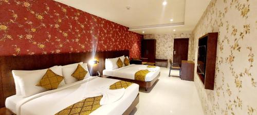 a hotel room with two beds and a red wall at Hotel Madhuban in Silvassa