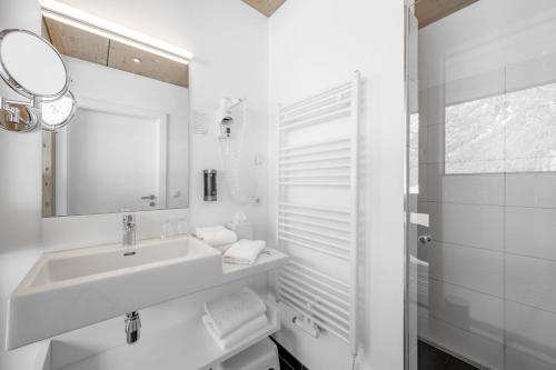 a white bathroom with a sink and a mirror at Hotel Fischer am See in Heiterwang