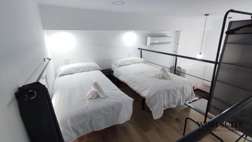 Habitación con 2 camas y sábanas blancas. en WISH SUITE MARIA AUXILIADORA DE SEVILLA, en Sevilla