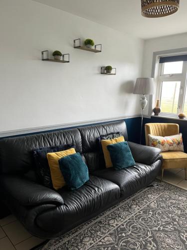 a black leather couch in a living room with pillows at Windmill cottage in Donegal