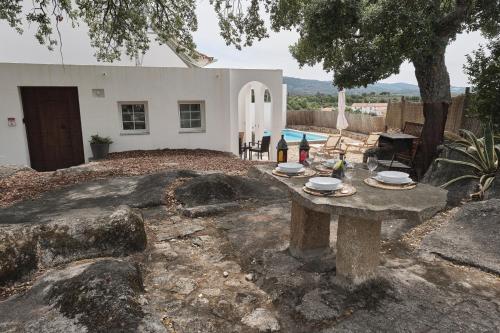 a table in front of a house with a pool at Casa do Brasão in Marvão