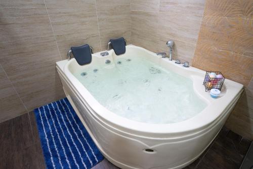 a large bath tub in a bathroom with a blue rug at Spacious 5 Bedroom Holiday Home Perfect for Gatherings BBQs Rumah Holiday Big 5BR House for 20 Guests - Ideal for Family Celebrations 宽敞整栋别墅 5 间大房间 20人 家庭聚会 生日派对 烧烤聚会 in Kuala Lumpur