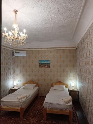 a bedroom with two beds and a chandelier at Khiva Ibrohim Guest House in Khiva