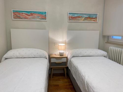 Habitación pequeña con 2 camas y mesa con lámpara. en VUT PLAZA DEL ANGEL, en Salamanca