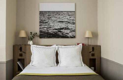 a bedroom with a bed with white pillows and a painting at Hôtel de la Place du Louvre - Esprit de France in Paris