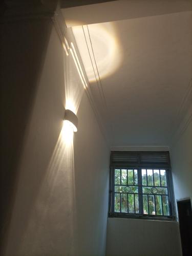 a light on a wall in a room with a window at Pearl Motel Buloba in Buloba
