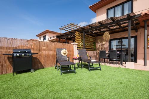 a backyard with a grill and chairs and a table at Villa Maha close by the North shore: relax, pool in Lajares