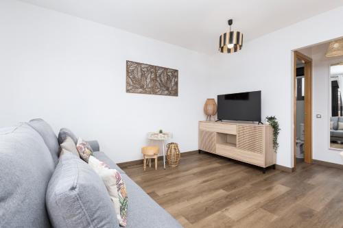 a living room with a gray couch and a tv at Villa Maha close by the North shore: relax, pool in Lajares
