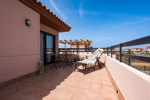 a balcony with chairs and tables on a building at Villa Maha close by the North shore: relax, pool in Lajares