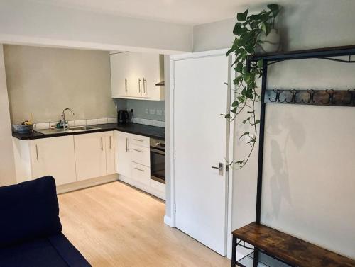 uma cozinha com armários brancos e uma porta aberta em Owl Tree Cottage with access to Alice Holt em Farnham