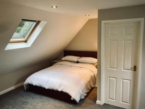 a bedroom with a bed with white sheets and a window at Owl Tree Cottage with access to Alice Holt in Farnham