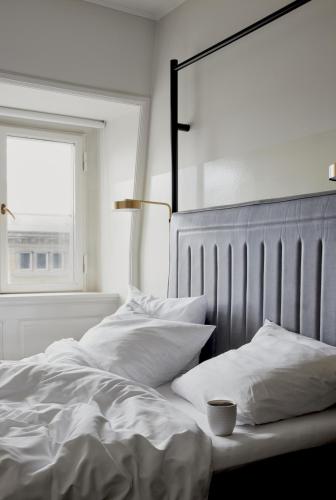 a bedroom with a bed with white sheets and a window at Hotel Danmark in Copenhagen