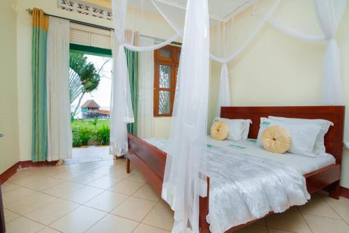 a bedroom with a canopy bed with a window at Mirembe Resort Beach Hotel Ssese in Kalangala