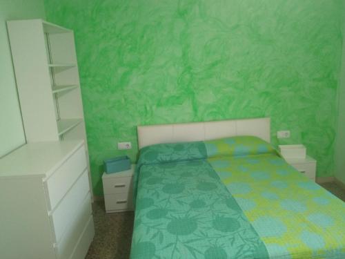 um quarto com uma cama e uma parede verde em Cal Turuta em Vilanova i la Geltrú