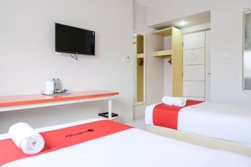 沙努爾的住宿－RedDoorz Plus at Sunrise Hotel Sanur，客房设有两张床和一台墙上的电视。