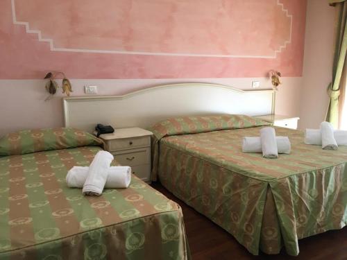 two beds in a hotel room with towels on them at Hotel Villa Strassoldo "Ex Attianese Hotel Restaurant" in Cervignano del Friuli