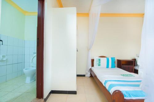 a small room with a bed and a toilet at Mirembe Resort Beach Hotel Ssese in Kalangala