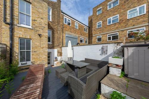 a patio with a table and benches in front of a building at Stylish 2 Bedroom Home in Islington with Garden in London